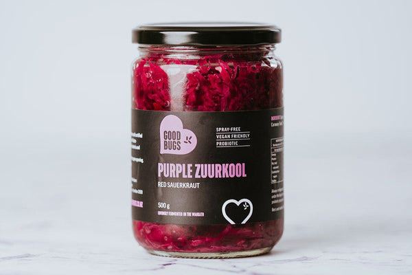A glass jar filled with purple sauerkraut, labeled 'Purple Zuurkool' with a white background.